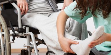 nurse helping a man in a wheelchair doing leg exercise