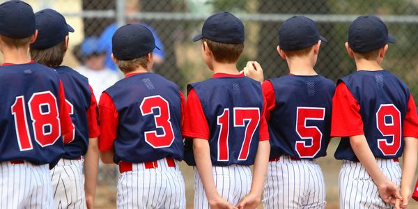 Young baseball players lined up with numbered jerseys.