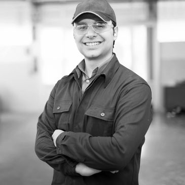Smiling factory worker in blue uniform and safety glasses.