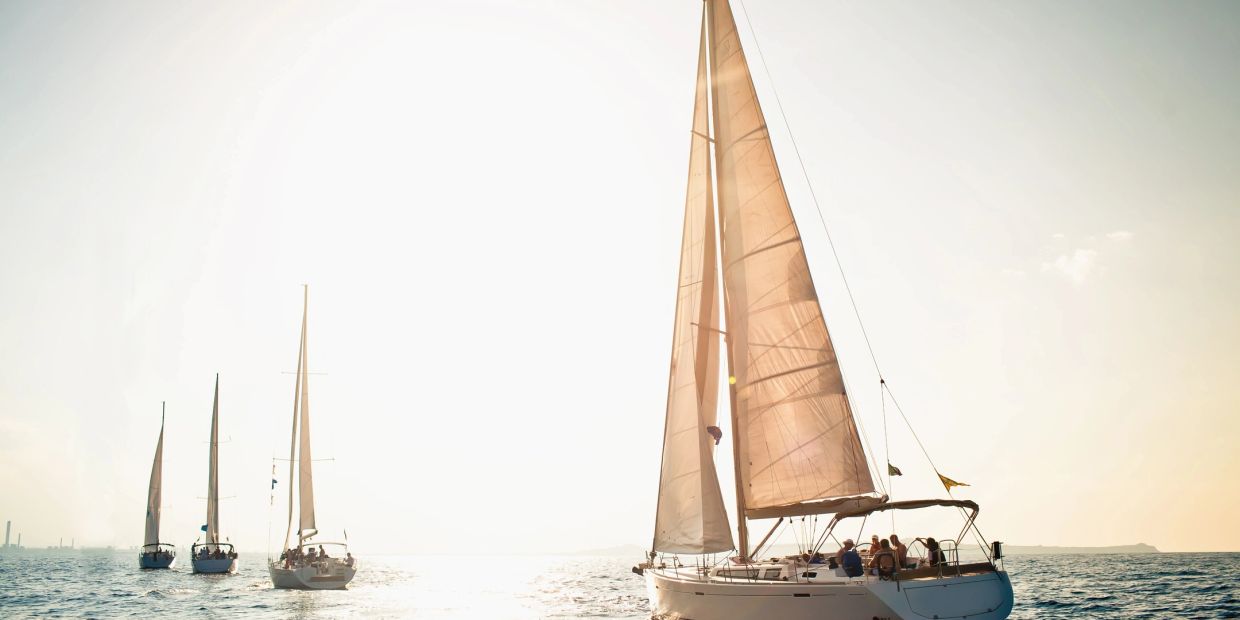 Sailboats gliding on the sea under a bright sky.
