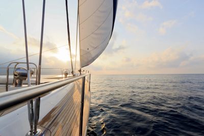 Sailing boat on calm sea at sunset.