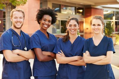 Four smiling adults wearing blue scrubs.