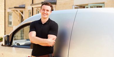 A male tradesman standing in front of his new work van.