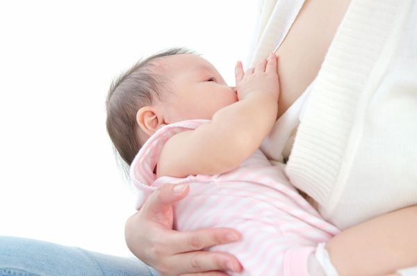 A baby breastfeeding from its mother, wrapped in a pink outfit.