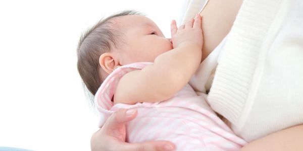 Baby nursing with her hand on the mother's breast