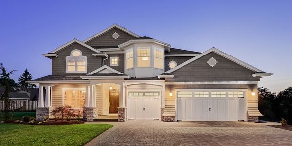 Gray and white two story house with lights on at dusk