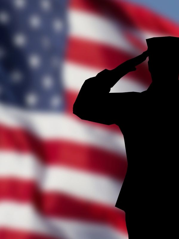 Silhouette of a soldier saluting with the American flag in the background.