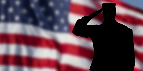 A shadow of a soldier saluting in front of an American flag.