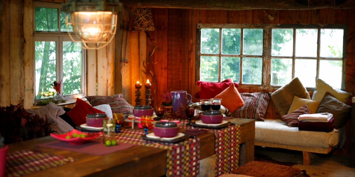 Cozy rustic dining area with candles and cushions.