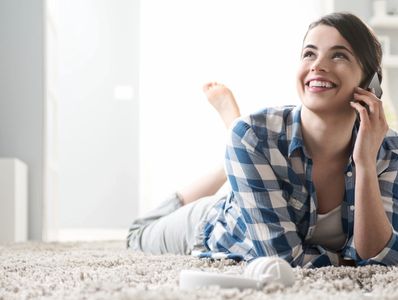 a young lady laying on her living room carpet speaking to a representative of Texas Med Group