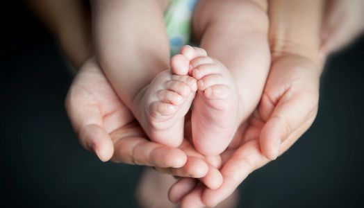 Baby with feet in adult hands.