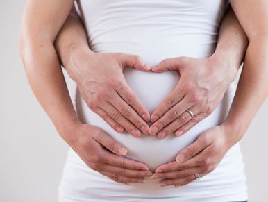 Hands forming a heart on a pregnant belly.