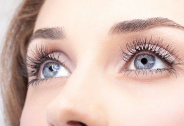 Close-up of bright blue eyes with long eyelashes and well-groomed eyebrows.