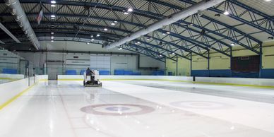 An ice resurfacer cleaning an ice rink indoors.