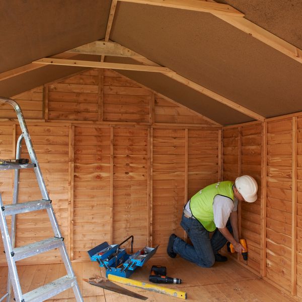 Construction worker fixing a wooden shed interior.