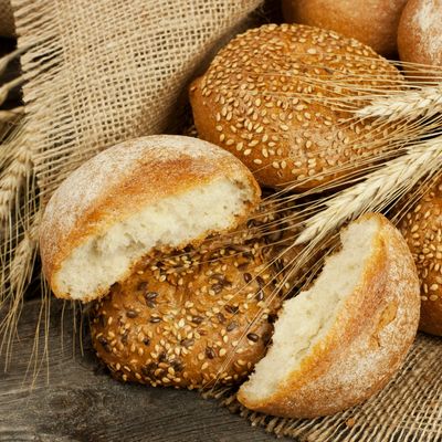 Freshly baked multigrain and sesame seed bread rolls on burlap.