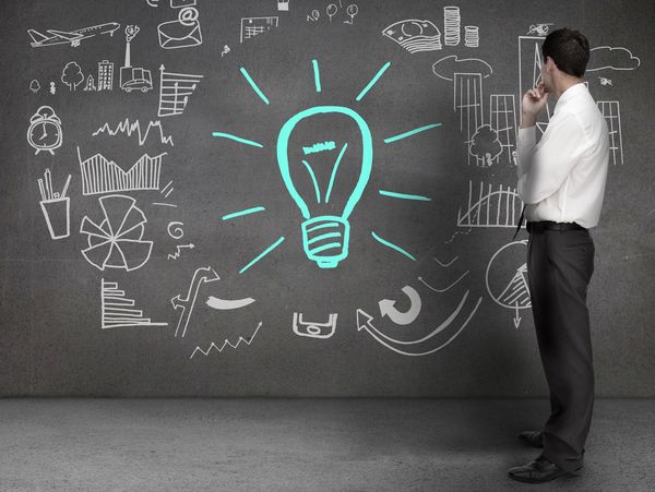 Businessman contemplating a glowing light bulb symbolizing ideas and innovation.