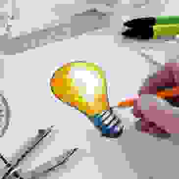 Drawing of lightbulb with other drawing materials in the background.