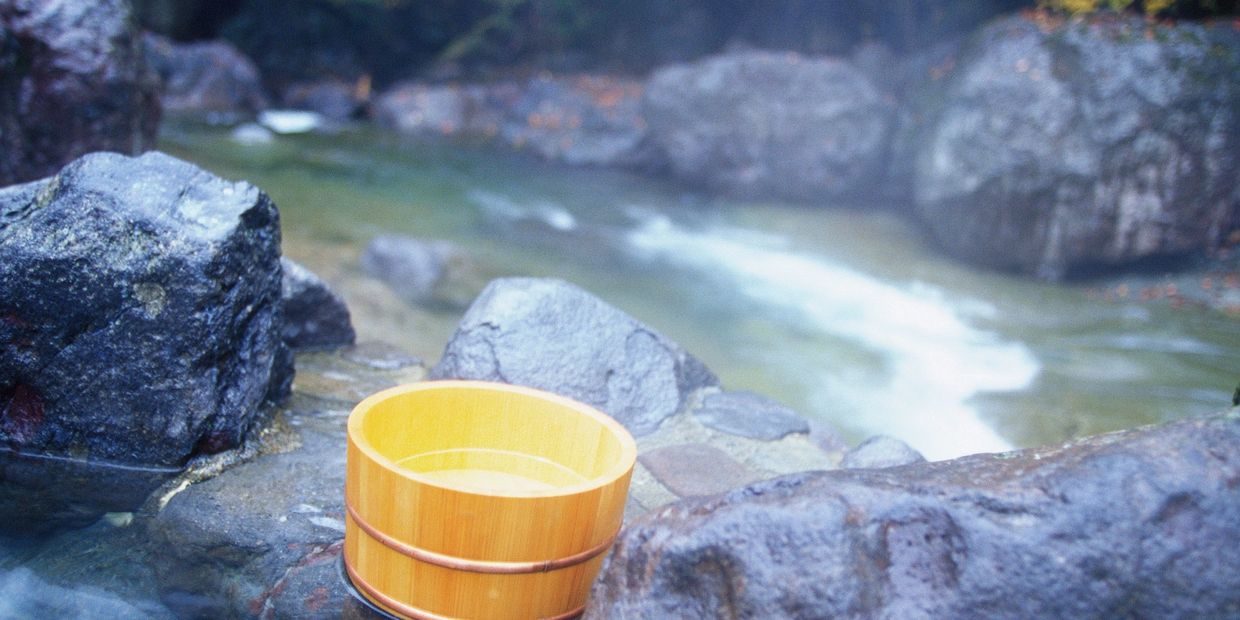 A wooden bucket sits on rocks beside a flowing river.