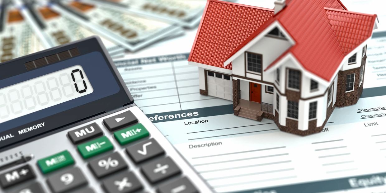 A calculator, cash, and a miniature house sit atop paperwork used to buy a new home. 