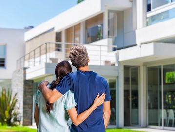 Couple embracing while admiring a modern house exterior.