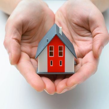 Hands holding a small model house in a gentle fashion.