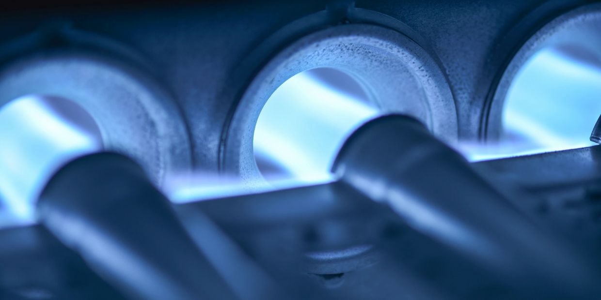 Close-up of blue flames burning inside a gas furnace burner.