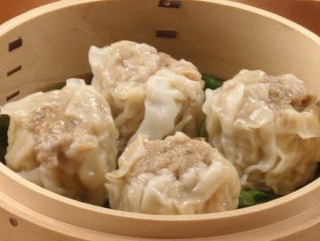 Steamed shumai dumplings served in a bamboo basket.