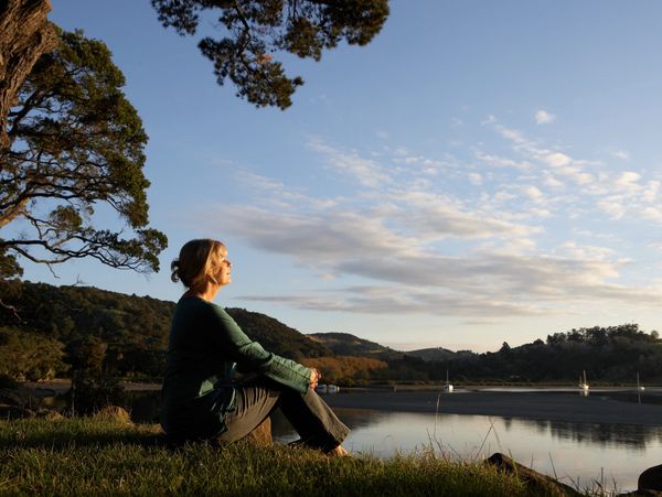 Woman sitting by a lake at sunset, enjoying the peaceful view.