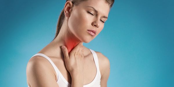 Woman holding her sore throat in pain.