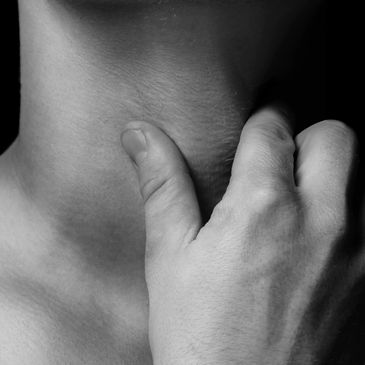 A hand gently touching a person's neck in black and white.