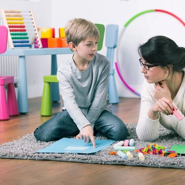 Speech therapist working with a boy pointing at something on paper.