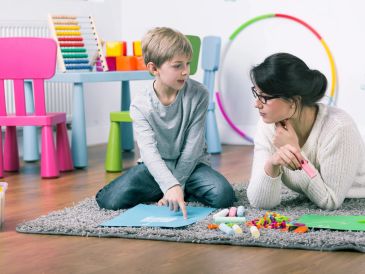 Boy and woman doing crafts on the floor.