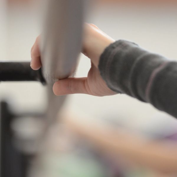 Hand gripping a ballet barre during practice.