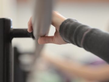 Hand gently holding a ballet barre during a dance class.