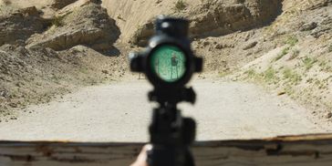 View through a rifle scope aimed at a target in a desert shooting range.