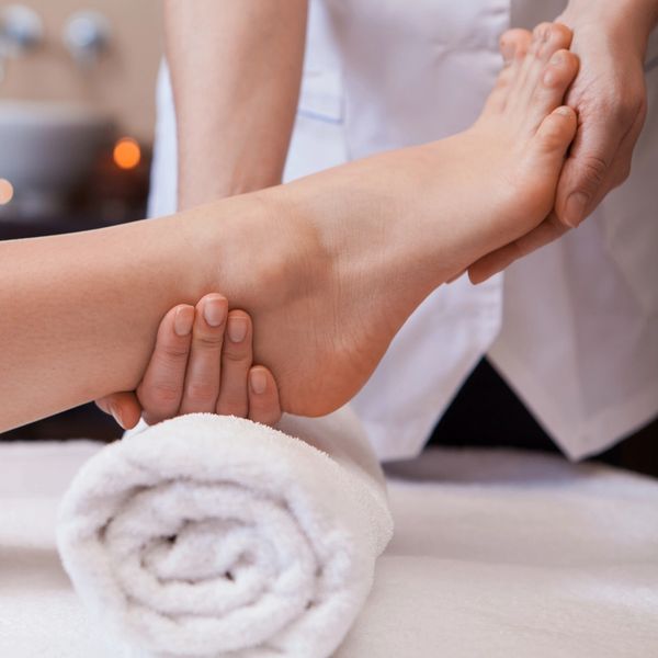 A reflexologist supports a patient's ankle as they perform a treatment.