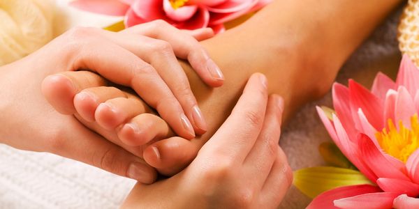 A woman massaging another woman's feet.
