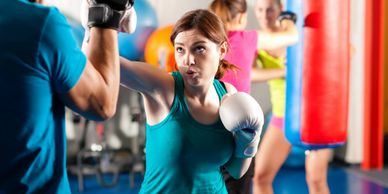 Woman boxing with a trainer in a gym.