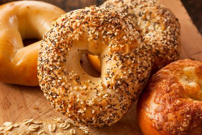 Assorted fresh bagels with various toppings on a wooden board.