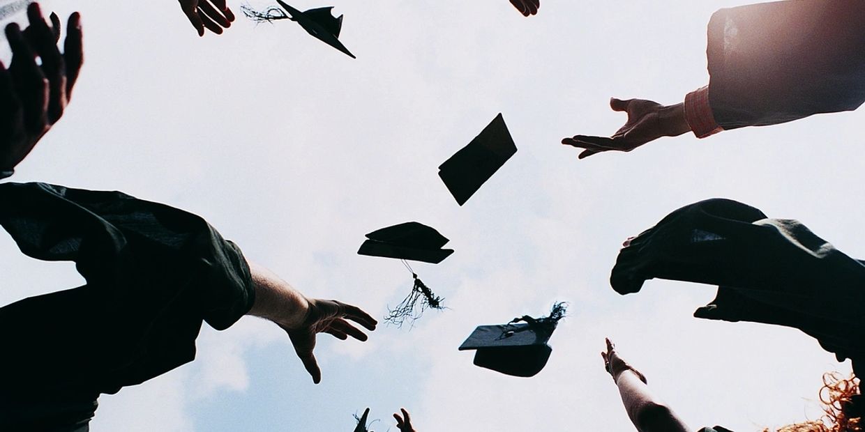 Graduates toss their caps into the sky in celebration.