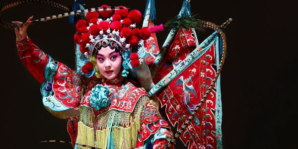 Performer in traditional Chinese opera costume with elaborate headpiece.