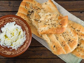 Flatbread with cream cheese and olive oil on a rustic table.