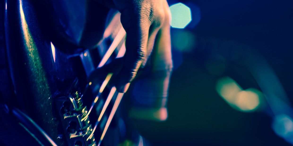 A close-up shot of a hand strumming guitar strings