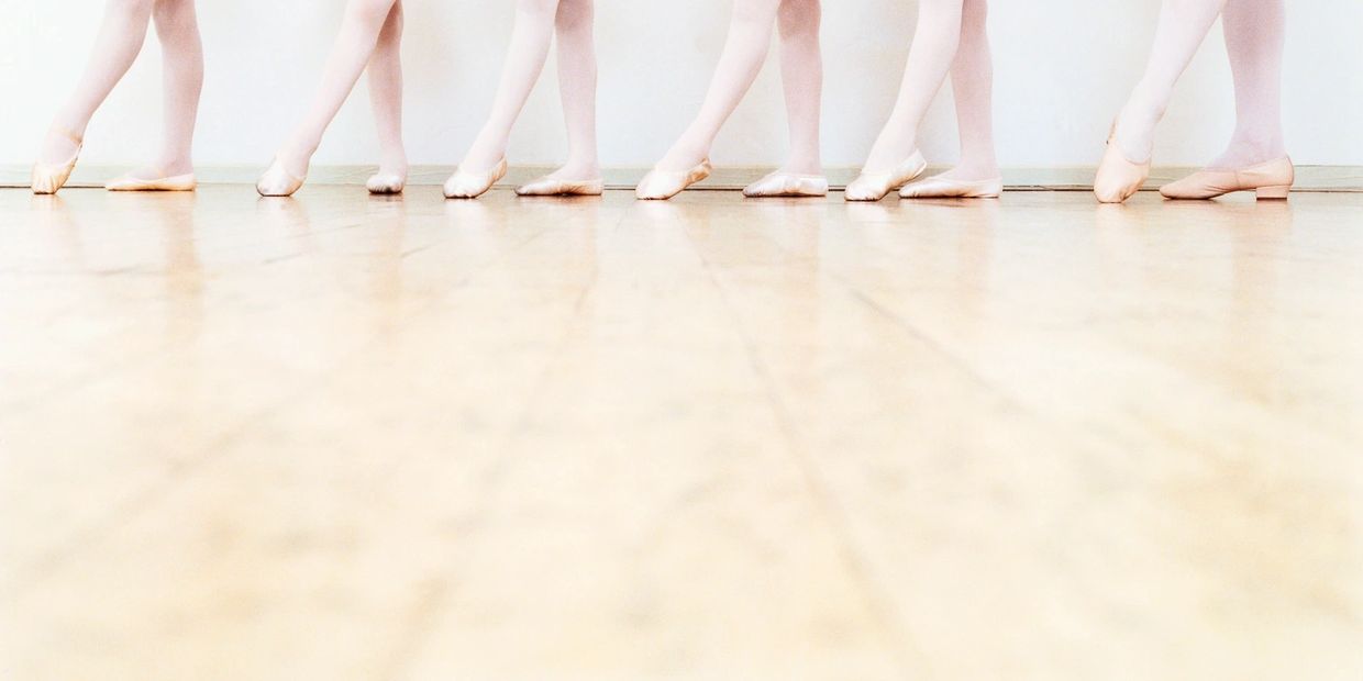 Ballet dancers' feet in pointe shoes lined up.
