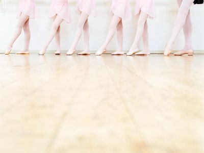 Ballet dancers in pink skirts standing on their toes.