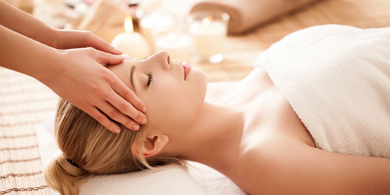 A woman is lying on a floor and receiving a massage and acupuncture treatment