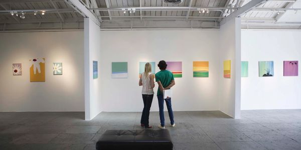 A man and a woman looking at paintings