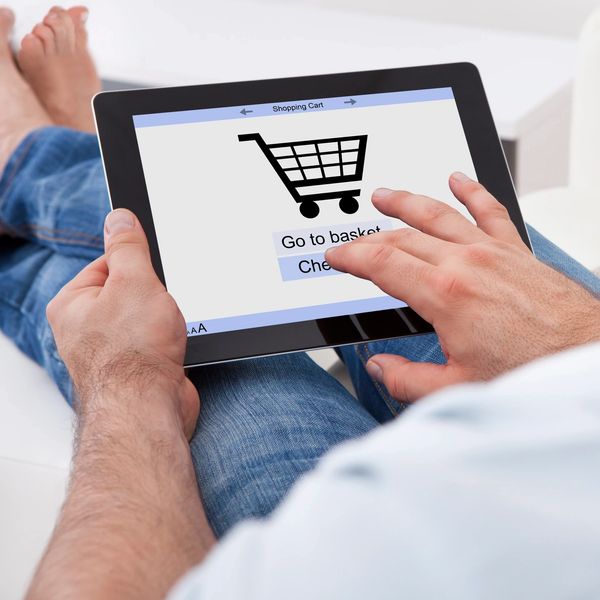 Person using a tablet to shop online with a visible shopping cart icon.