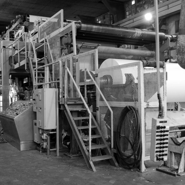 Industrial paper manufacturing machine with large paper roll in factory.